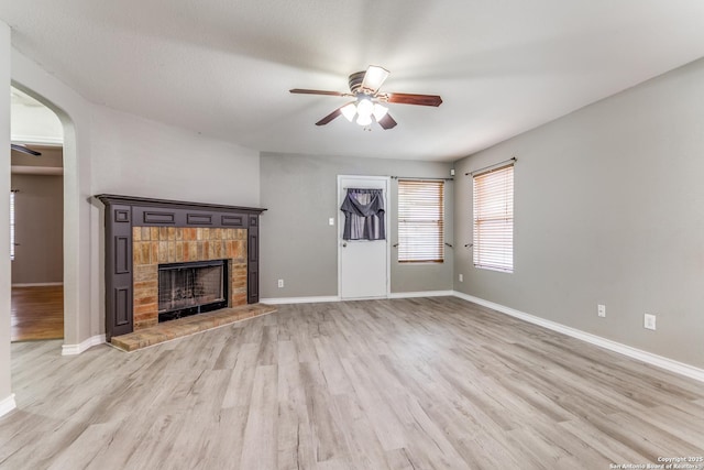 unfurnished living room featuring a fireplace, ceiling fan, and light hardwood / wood-style flooring