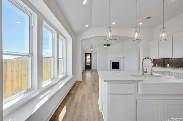 kitchen featuring tasteful backsplash, vaulted ceiling, sink, pendant lighting, and white cabinets