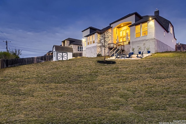 rear view of property featuring a lawn and a storage shed