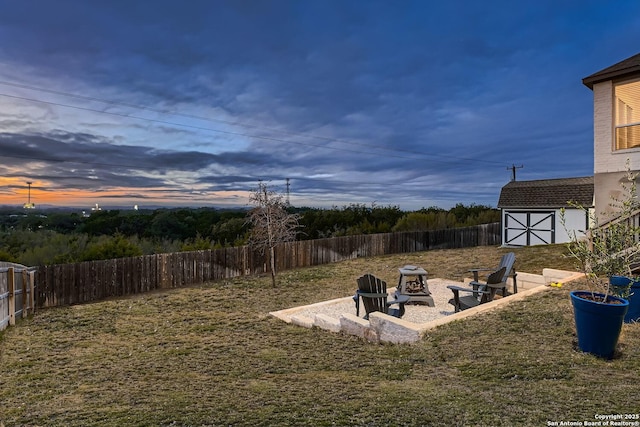 yard at dusk with a patio area, a shed, and an outdoor fire pit