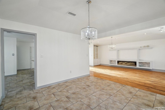 unfurnished living room with light tile patterned floors, a fireplace, and a chandelier