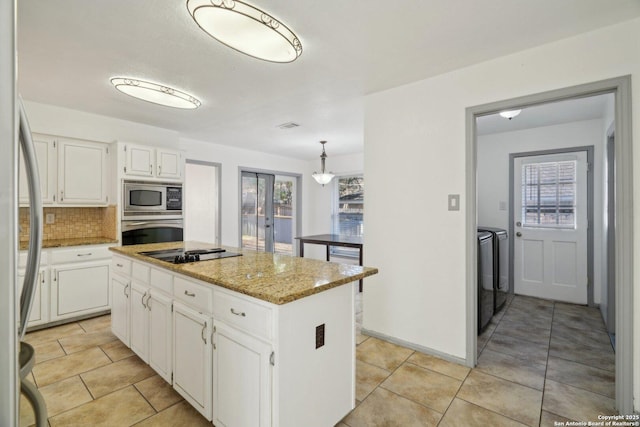 kitchen featuring backsplash, stainless steel appliances, independent washer and dryer, a center island, and white cabinetry