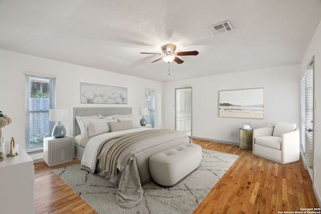 bedroom with multiple windows, a textured ceiling, light hardwood / wood-style flooring, and ceiling fan