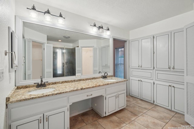 bathroom with tile patterned flooring, vanity, and a textured ceiling