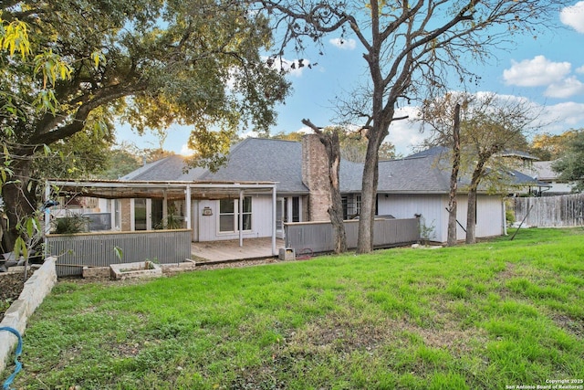 back of house featuring a lawn and a deck