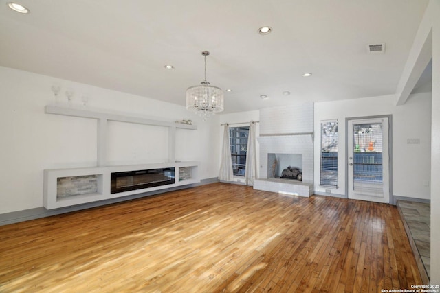 unfurnished living room with a fireplace, hardwood / wood-style floors, and a chandelier