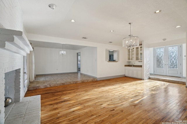 unfurnished living room featuring a notable chandelier, a fireplace, and light hardwood / wood-style flooring