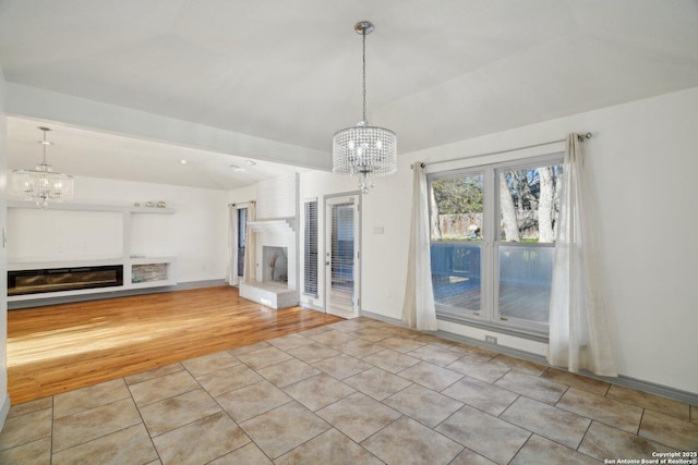 unfurnished living room featuring an inviting chandelier, light tile patterned floors, and a brick fireplace