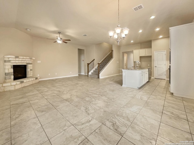 unfurnished living room with ceiling fan with notable chandelier, sink, and a fireplace