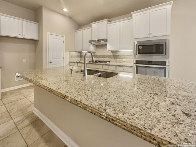 kitchen with appliances with stainless steel finishes, white cabinetry, and light stone counters