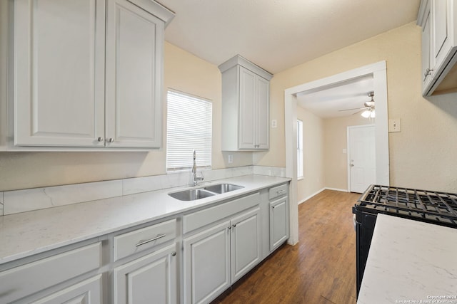 kitchen featuring white cabinetry, dark hardwood / wood-style flooring, black gas range oven, and sink