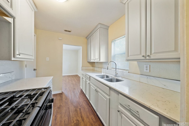 kitchen featuring white cabinetry, sink, dark wood-type flooring, light stone counters, and stainless steel range with gas stovetop