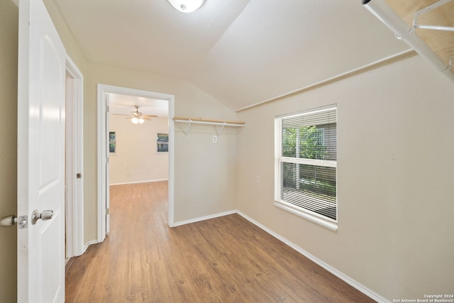 walk in closet with ceiling fan, vaulted ceiling, and light hardwood / wood-style flooring