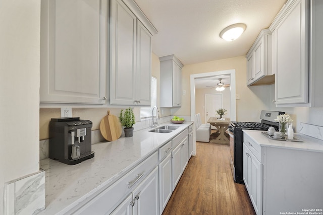 kitchen featuring dark hardwood / wood-style flooring, stainless steel gas stove, white cabinets, and sink