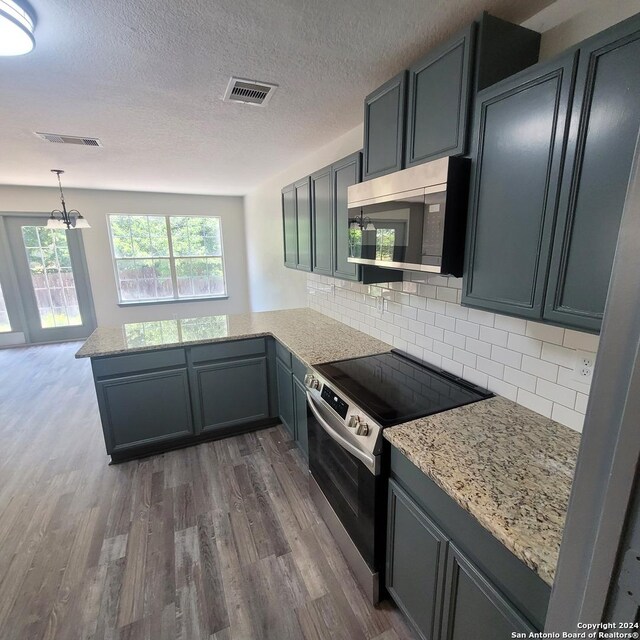 kitchen with kitchen peninsula, dark hardwood / wood-style flooring, stainless steel appliances, and tasteful backsplash