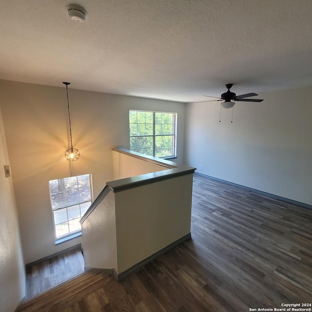 interior space with ceiling fan, dark wood-type flooring, and a textured ceiling