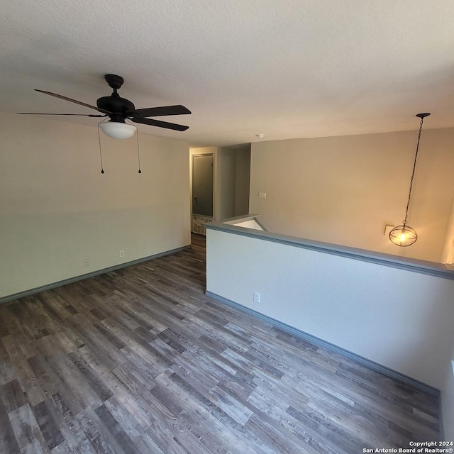 spare room featuring dark hardwood / wood-style floors, ceiling fan, and a textured ceiling