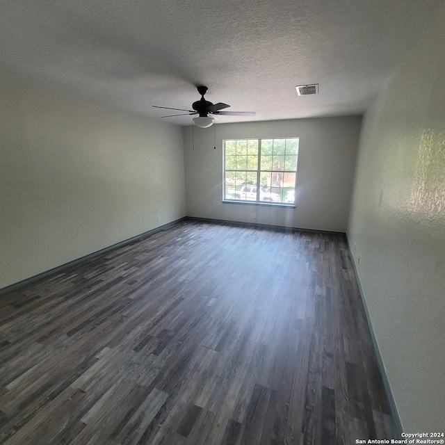 empty room with a textured ceiling, ceiling fan, and dark hardwood / wood-style floors