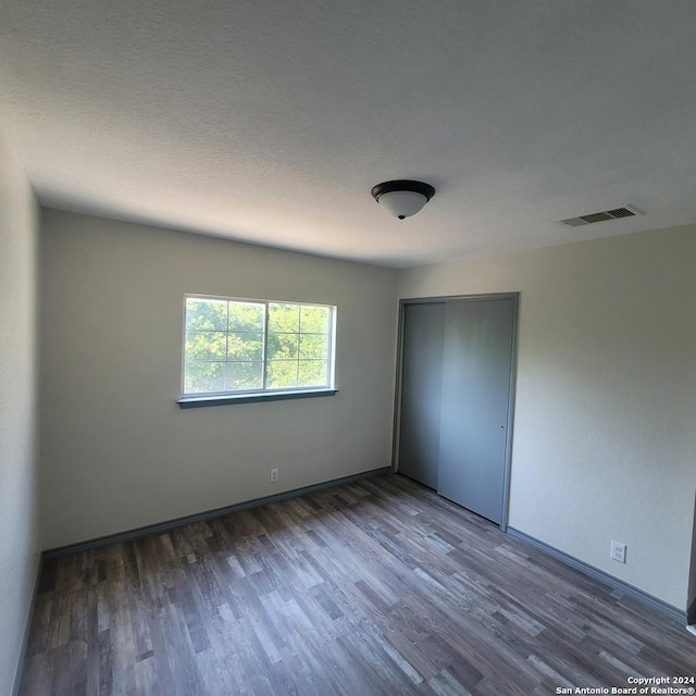 unfurnished bedroom featuring a closet and dark wood-type flooring