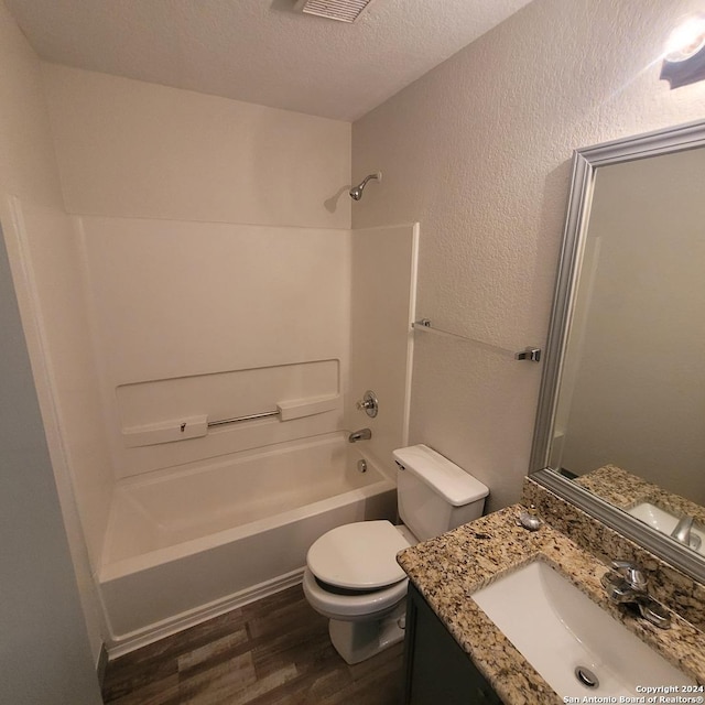 full bathroom featuring vanity, hardwood / wood-style flooring, toilet, a textured ceiling, and shower / bathtub combination