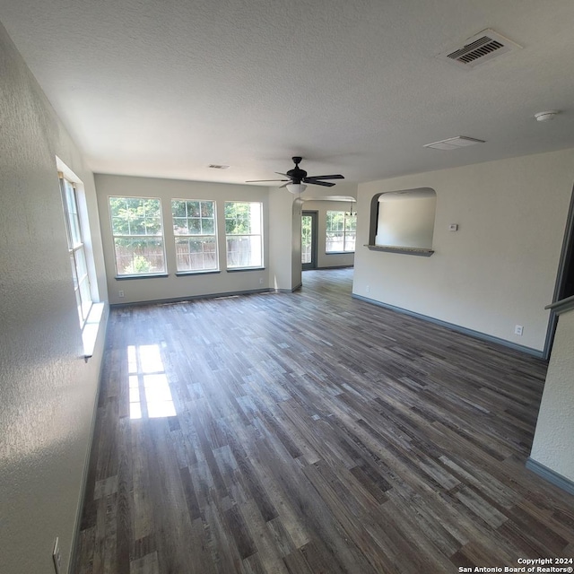 unfurnished living room with a textured ceiling, dark hardwood / wood-style flooring, and ceiling fan