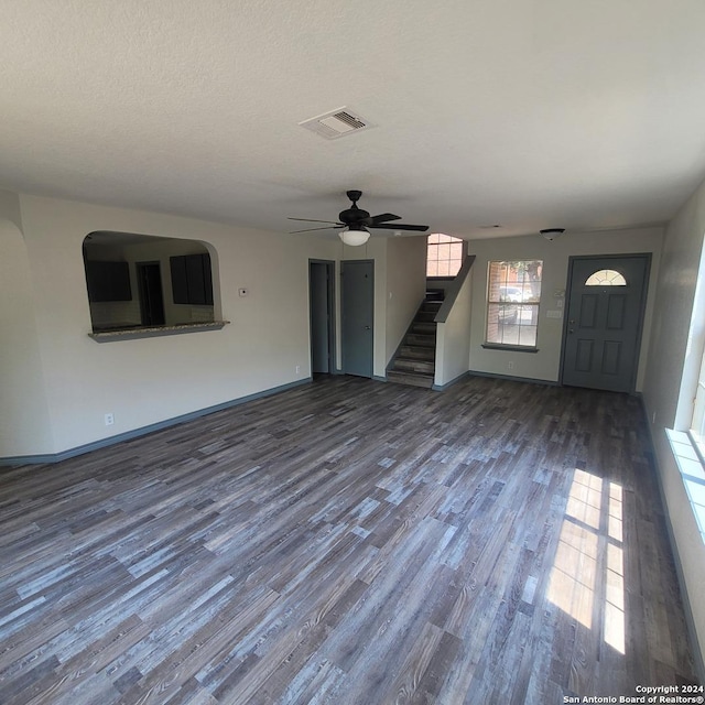 unfurnished living room with a textured ceiling, ceiling fan, and dark hardwood / wood-style floors