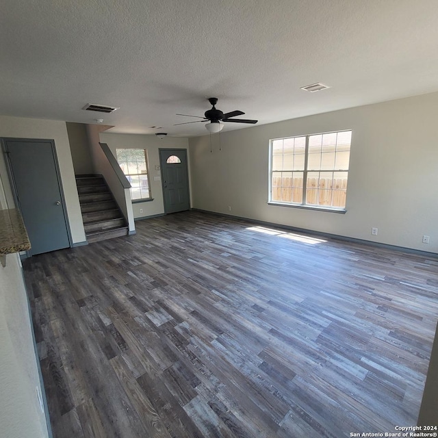 unfurnished living room featuring a textured ceiling, ceiling fan, and dark wood-type flooring