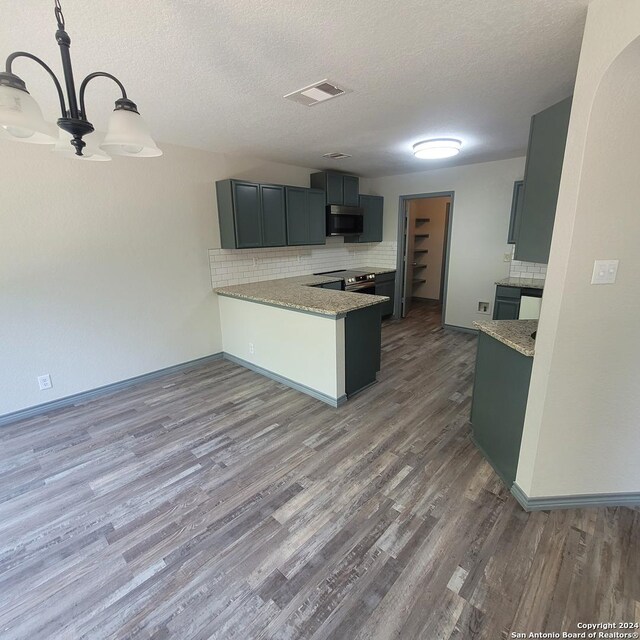 kitchen with kitchen peninsula, appliances with stainless steel finishes, light stone counters, a textured ceiling, and hardwood / wood-style floors