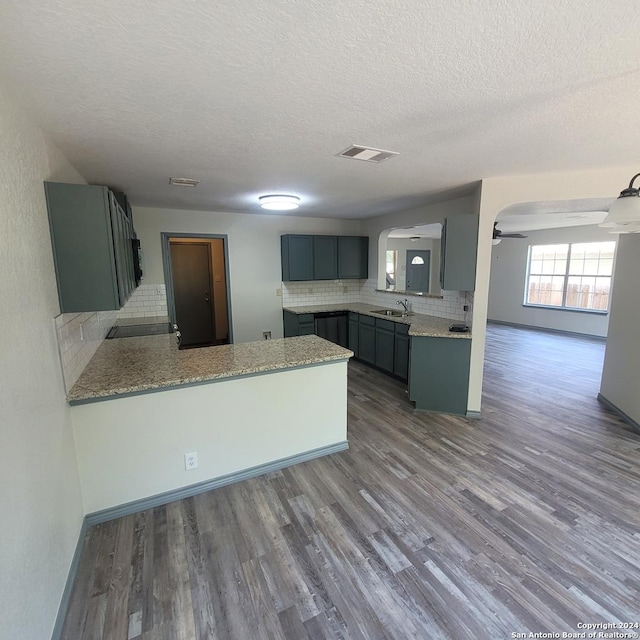 kitchen featuring hardwood / wood-style floors, sink, decorative backsplash, ceiling fan, and kitchen peninsula