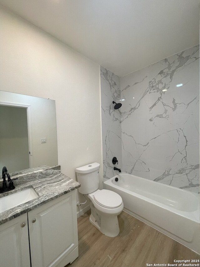 full bathroom with hardwood / wood-style floors, toilet, tiled shower / bath, and vanity