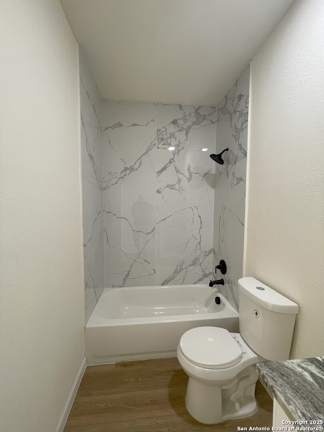 bathroom featuring toilet, hardwood / wood-style floors, and tiled shower / bath combo