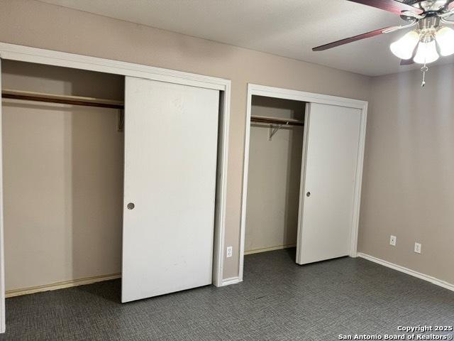 unfurnished bedroom with ceiling fan, baseboards, and multiple closets