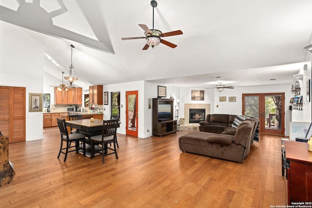 living room with french doors, high vaulted ceiling, and light hardwood / wood-style flooring