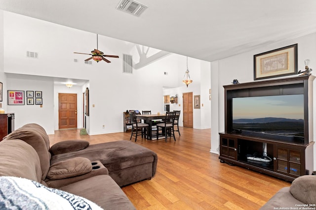 living room with a high ceiling, light hardwood / wood-style floors, and ceiling fan