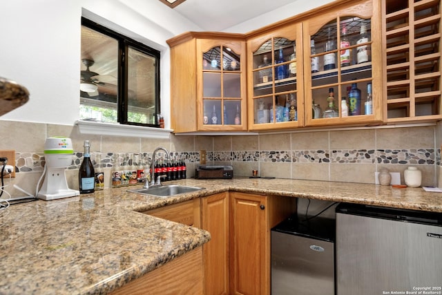 kitchen with tasteful backsplash, light stone countertops, sink, and ceiling fan