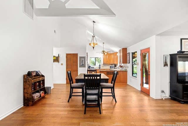 dining space with ceiling fan, high vaulted ceiling, and light wood-type flooring