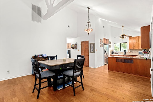 dining space featuring ceiling fan, high vaulted ceiling, and light wood-type flooring