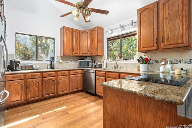 kitchen with appliances with stainless steel finishes, tasteful backsplash, light stone counters, and sink