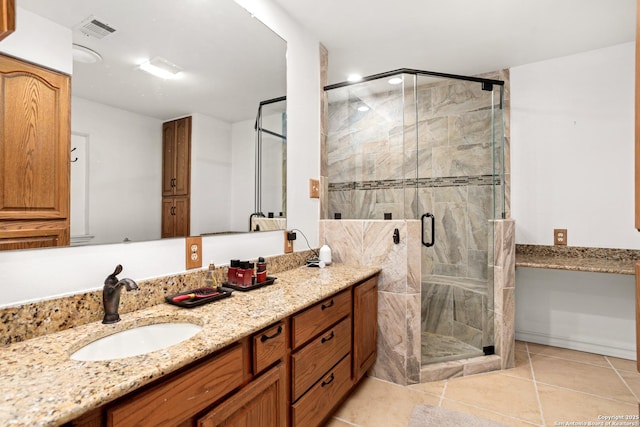 bathroom with a shower with door, vanity, and tile patterned flooring