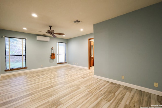 empty room featuring a wall unit AC, ceiling fan, and light hardwood / wood-style flooring