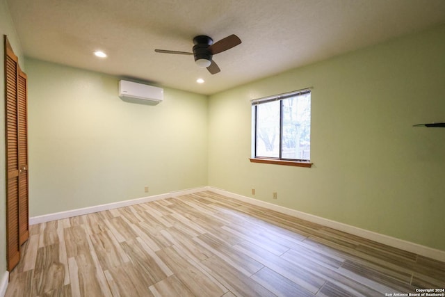 empty room featuring ceiling fan, an AC wall unit, and light hardwood / wood-style flooring