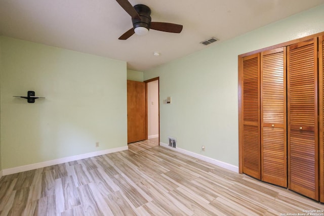 unfurnished bedroom featuring ceiling fan, light hardwood / wood-style floors, and a closet