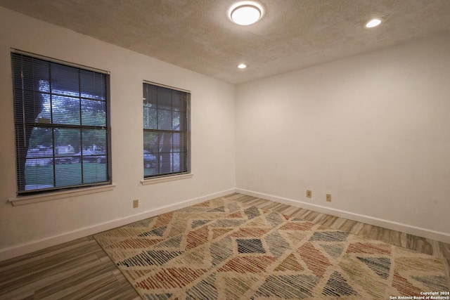 empty room featuring wood-type flooring and a textured ceiling