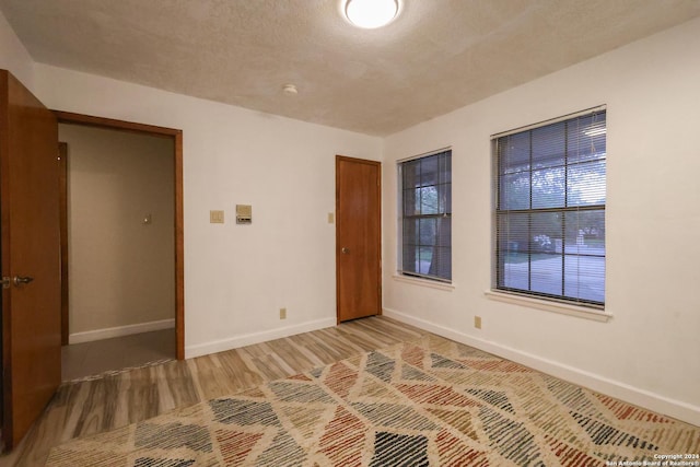 empty room with hardwood / wood-style floors and a textured ceiling