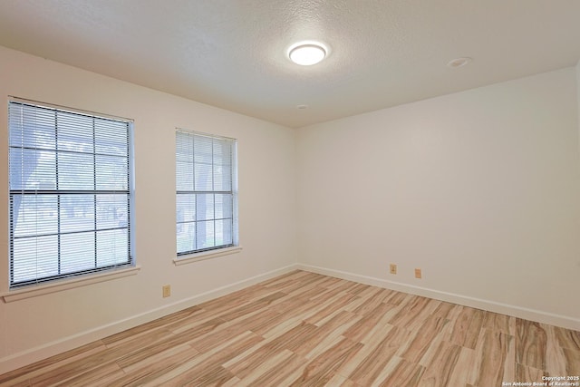 unfurnished room with a textured ceiling and light hardwood / wood-style floors