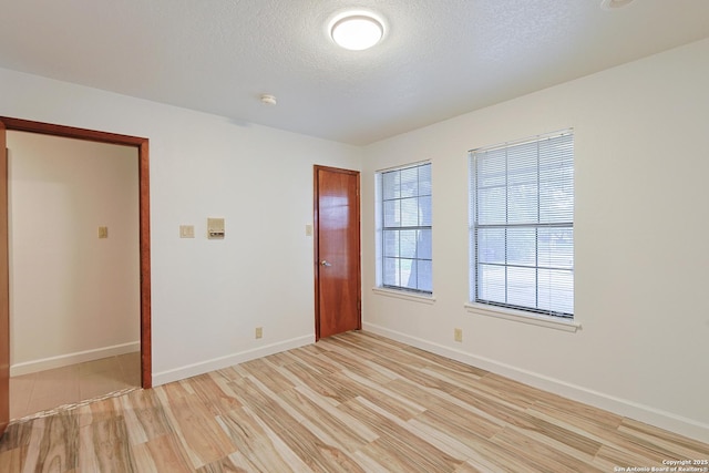 spare room with light hardwood / wood-style floors and a textured ceiling