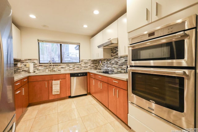 kitchen with appliances with stainless steel finishes, backsplash, sink, light tile patterned floors, and white cabinetry