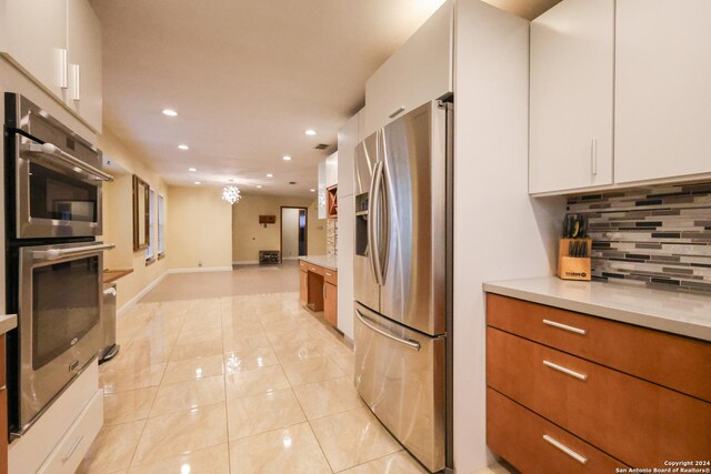 kitchen with white cabinets, light tile patterned floors, backsplash, and appliances with stainless steel finishes