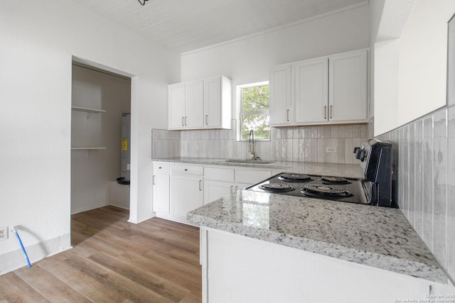 kitchen featuring light wood-type flooring, light stone counters, sink, white cabinets, and range