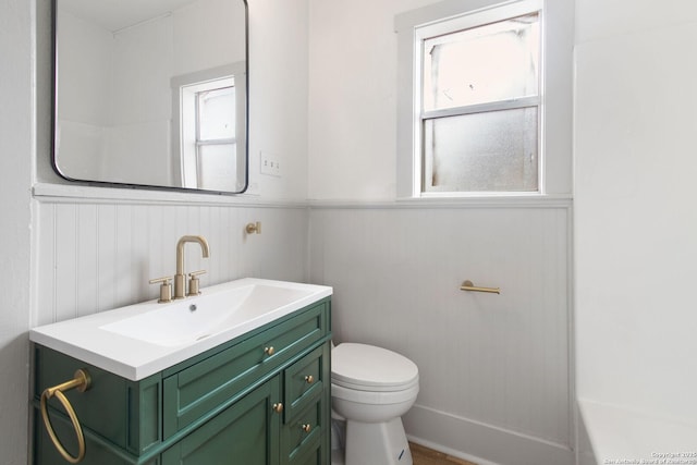 bathroom featuring a wealth of natural light, vanity, wood walls, and toilet